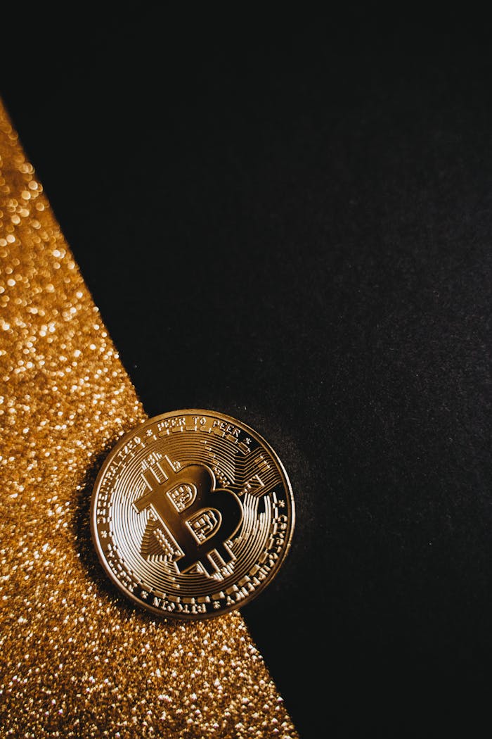 home-hero Close-up of a shiny Bitcoin coin on a black surface, accented by sparkling gold glitter.